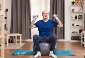 senior man lifting weights in living room